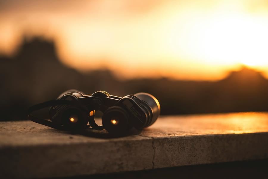 binoculars sitting on the edge of the railing, outdoors