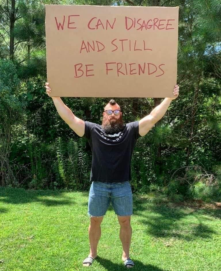 man outdoors, holding up a sign, we can disagree and still be friends