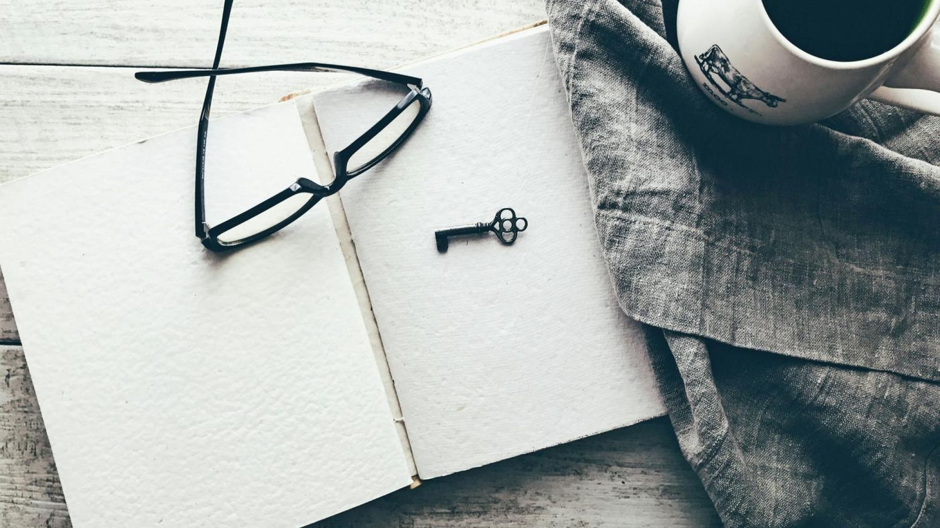 key and glasses on a note pad on a desk indoors