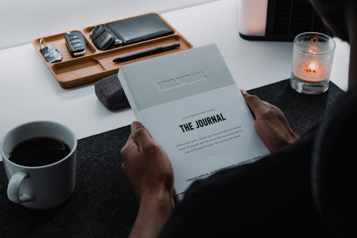 person sitting at a desk, drinking and journaling