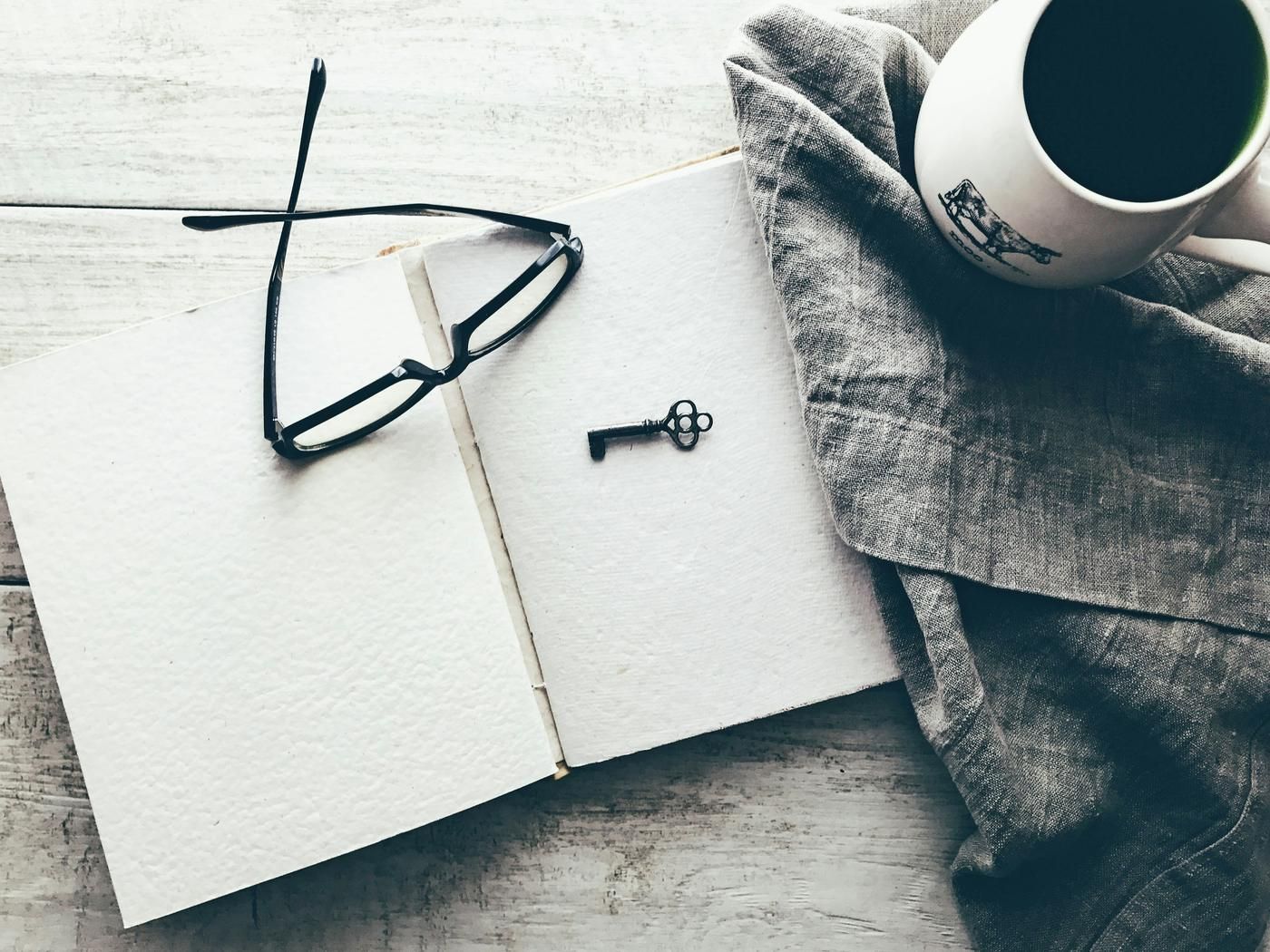 key and glasses on a note pad on a desk indoors