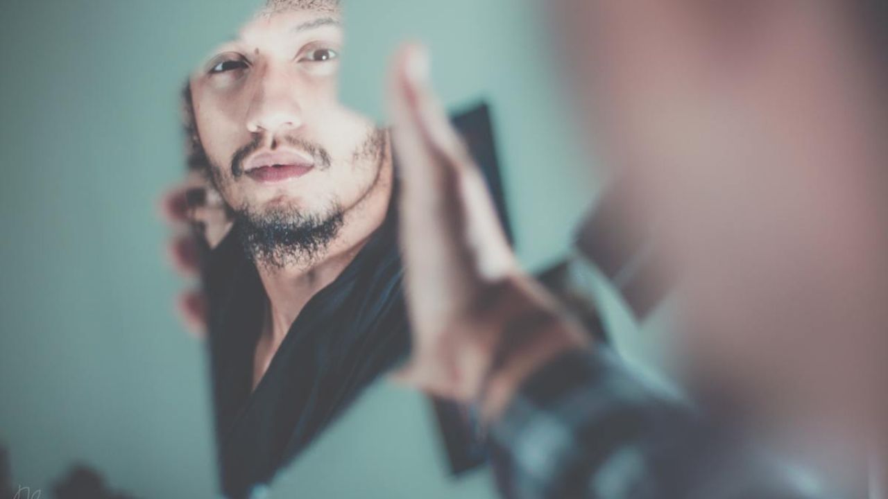 a man looking into a broken piece of a mirror