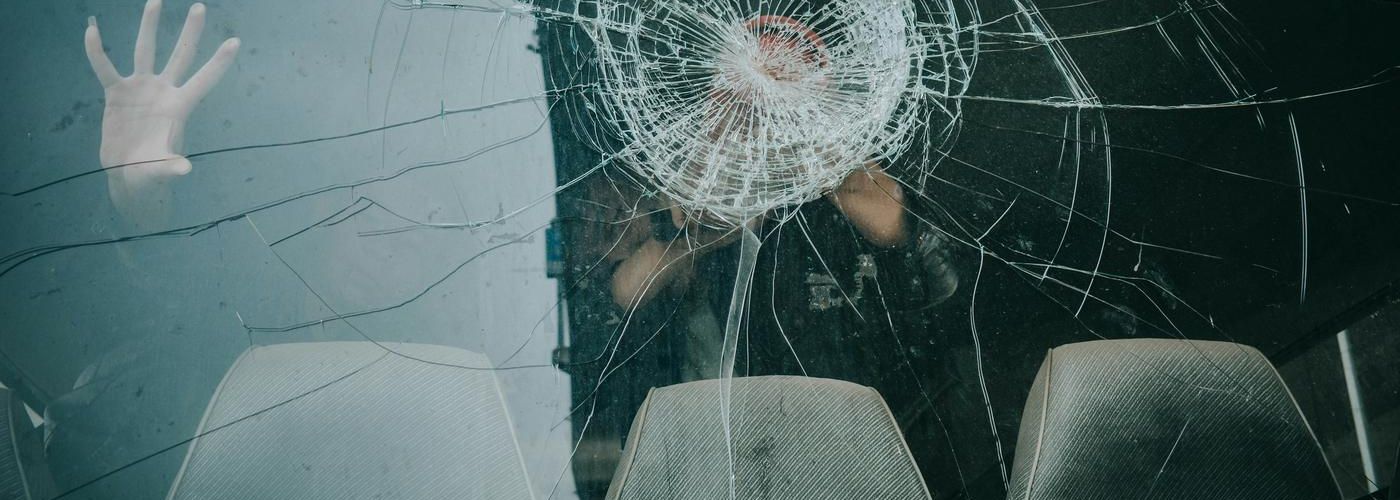 hand inside car on cracked windshield