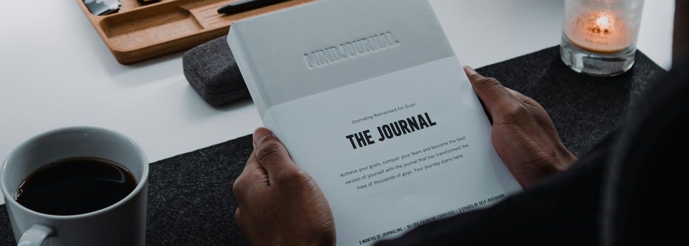 person sitting at a desk, drinking and journaling