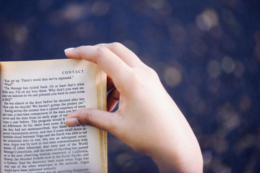 person reading a book indoors, with hand on book