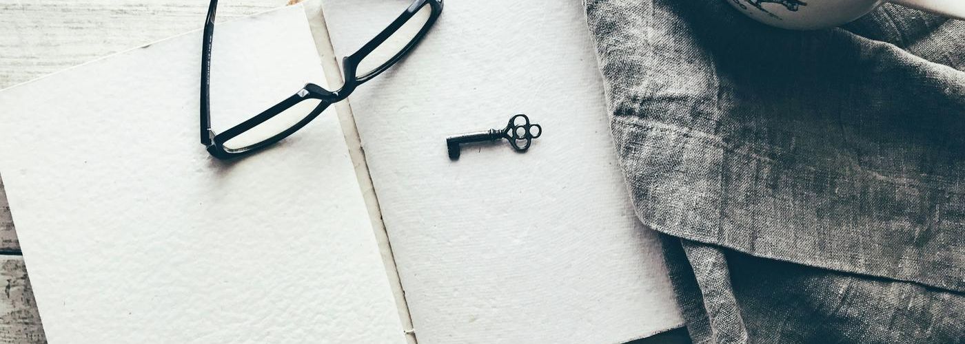 key and glasses on a note pad on a desk indoors