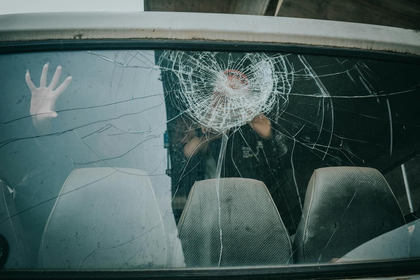 hand inside car on cracked windshield