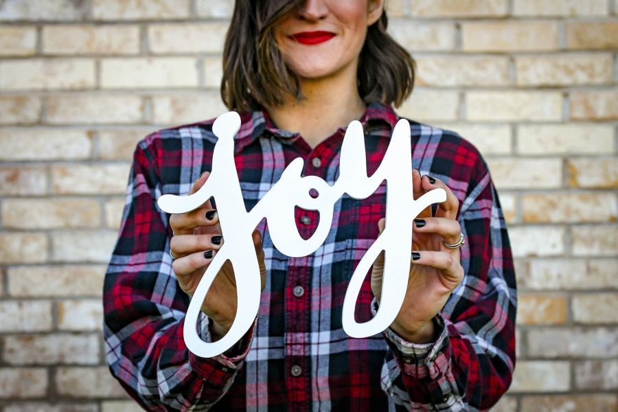 A picture of a woman, outside, holding a joy sign